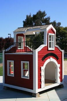 Red and white playhouse on a playground.
