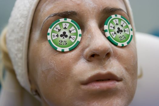 Poker chips lying on eyes like cucumbers in spa salon