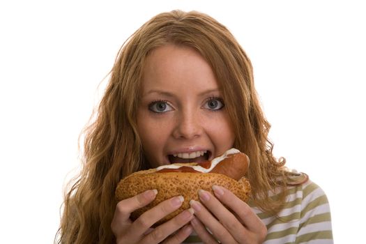 red-haired girl eating a hot dog on a light background