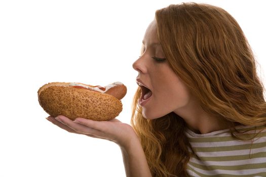 red-haired girl eating a hot dog on a light background