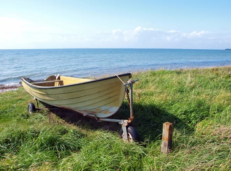 Beach landscape - small colorful skiff on the sand  