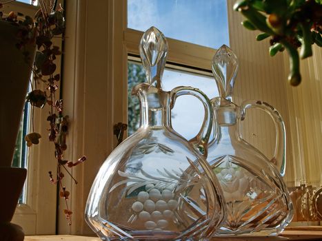 Closeup of Beautiful antique glass carafes bottles in a window shelf      