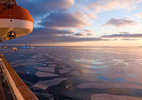 Lighthouse in the Arctic Sea at sunset. View from the boat