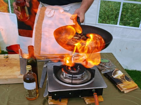 Chef in a restaurant cooks in flambe flames      