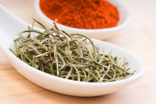 Aromatic dried rosemary in a white spoon.