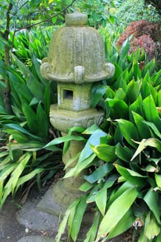 Close up of a japanese statue in a garden.
