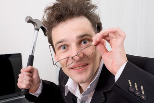 The businessman in spectacles gone mad with a hammer in a hand