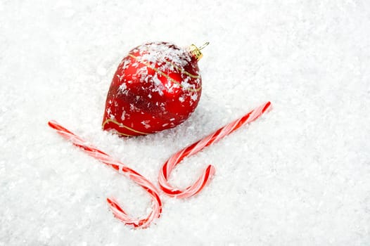 Image of candy canes and an ornament lying in the snow