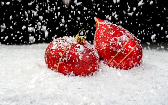 Image of snow falling on two red ornaments