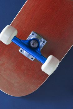 the underside of a red coloured skateboard on a blue background