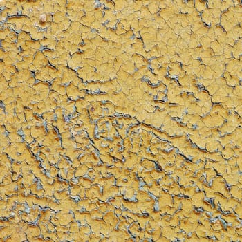 Yellow aged painted wall with numerous cracks
