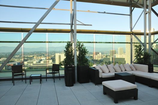 Chairs and a couch provide a place to enjoy the downtown sunset from a highrise rooftop