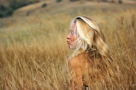 Girl sitting on straw grass in the valley