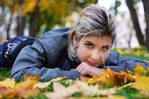 Girl lying on the ground covered with maple leaves