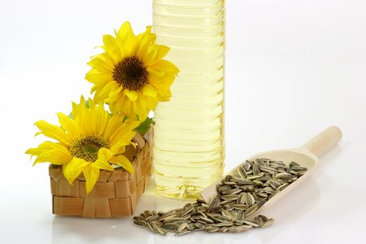 Cooking oil in a plastic bottle with sunflower seeds on white background