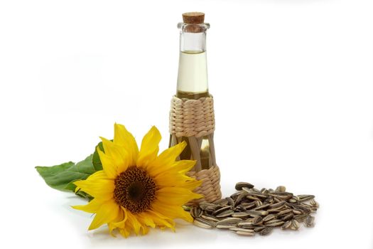 Salad oil in a glass bottle with sunflower and sunflower seeds on white background