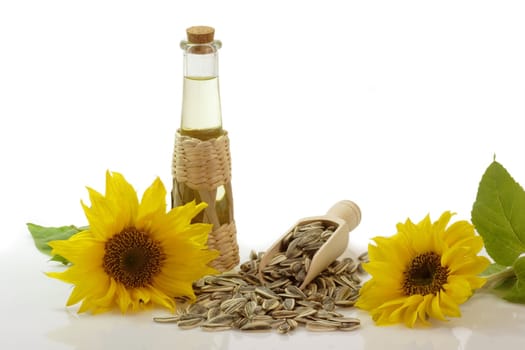 Salad oil in a glass bottle with sunflower seeds on white background