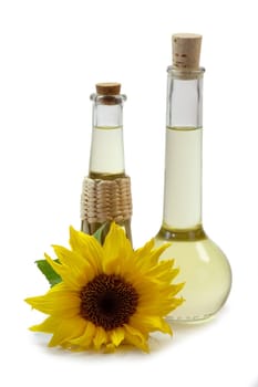 Salad oil in bottles with sunflowers on white background