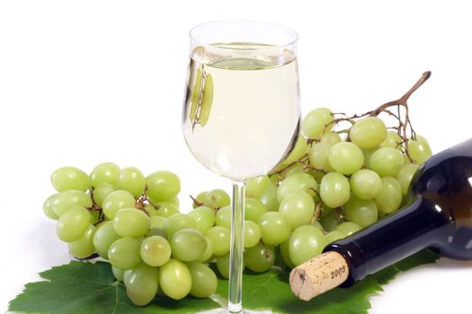 Glass of white wine with bottle and grapes on bright background