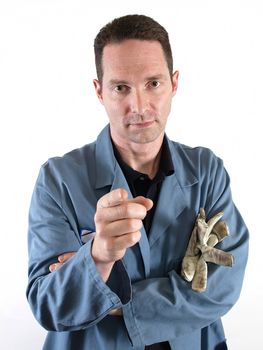 A male worker in a blue smock points his finger while looking straight at the camera.