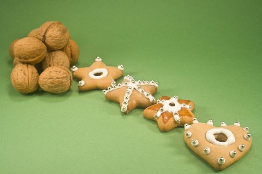 Christmas cookies and a pile of walnuts isolated on green paper