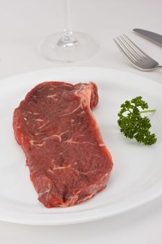 raw steak on a white plate with cutlery
