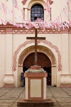 Cross in front of a pink painted church in Chiapas, Mexico