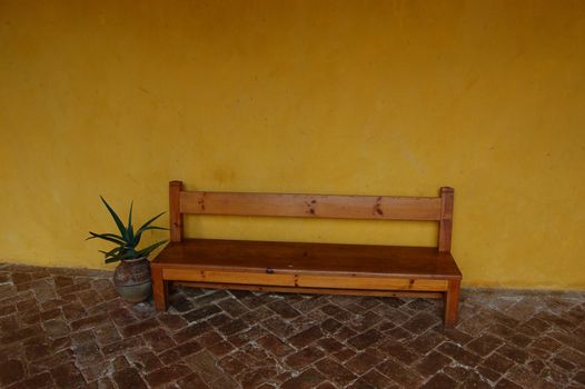 Bench against a yellow wall and tile floor in Chiapas Convent