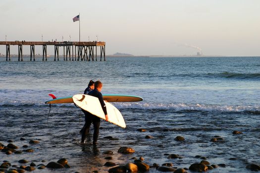 Surfer at sunset at the beach near the pier in Ventura California.