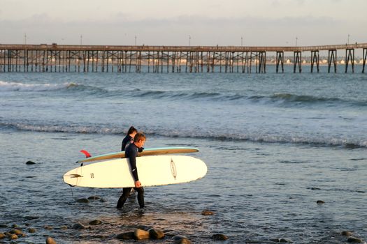 Surfer at sunset at the beach near the pier in Ventura California.