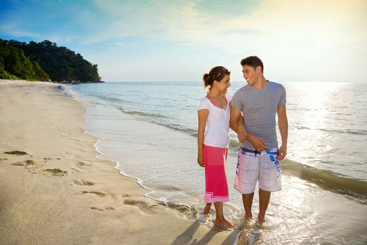 happy couple walking along a romantic sunset beach