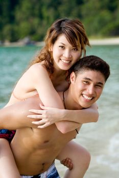 couple carrying piggyback on a tropical beach
