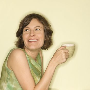 Pretty Caucasian mid-adult woman holding up coffee cup and smiling.