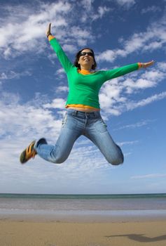 Young beautiful woman making a big jump on the beach