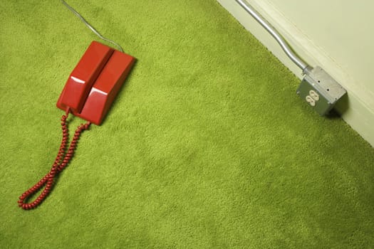 Red vintage telephone on 70's green carpet.