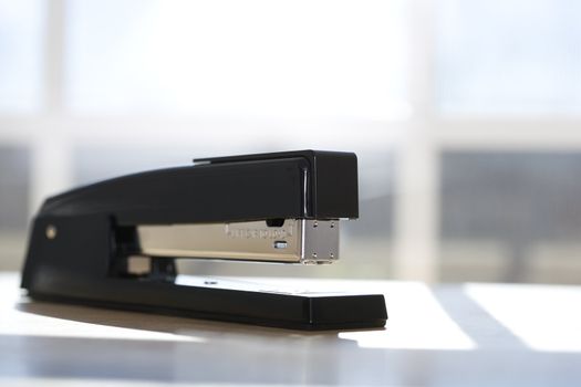 Black stapler with window in background.