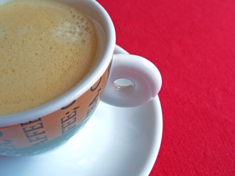 Cup of creamy coffee on red background