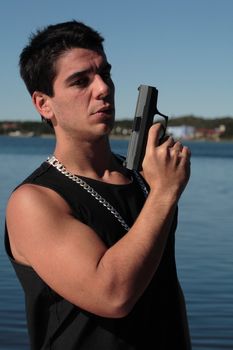 A young man, wearing a sleeveless shirt, holding a hand gun. (This image is part of a series)