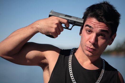 A young man, wearing a sleeveless shirt, holding a hand gun. (This image is part of a series)