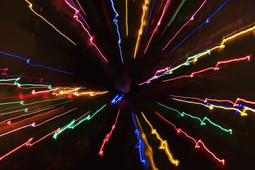 Multicolored lights forming abstract radial starburst pattern from motion blur.