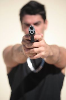 A young man, wearing a sleeveless shirt, holding a hand gun. (This image is part of a series)