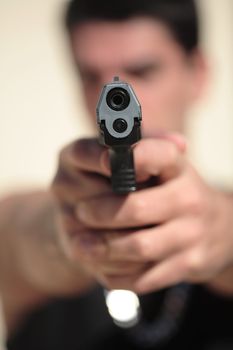 A young man, wearing a sleeveless shirt, holding a hand gun. (This image is part of a series)