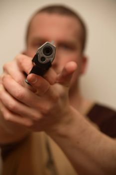 A young man holding a pistol towards the camera.