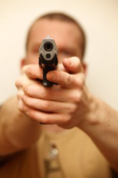 A man holding a pistol and pointing it at the camera.