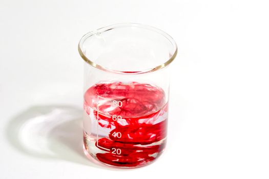 Graduated beaker with red fluid on bright background