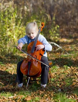 Child player her cello outside on an October afternoon.