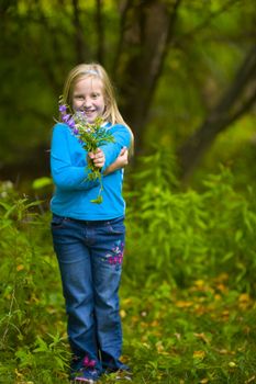 Wildflowers presented by girl in blue in a green forest