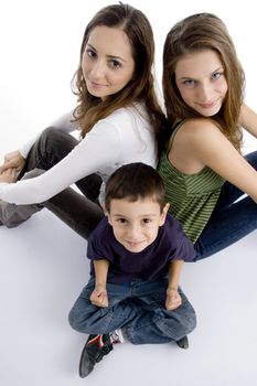 young kid sitting with teenagers and facing at camera all, on an isolated white background