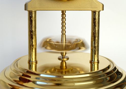 Rotating pendulum of a golden-coloured clock.

