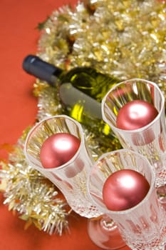 Three glasses with wine bottle and Christmas decoration on red background.